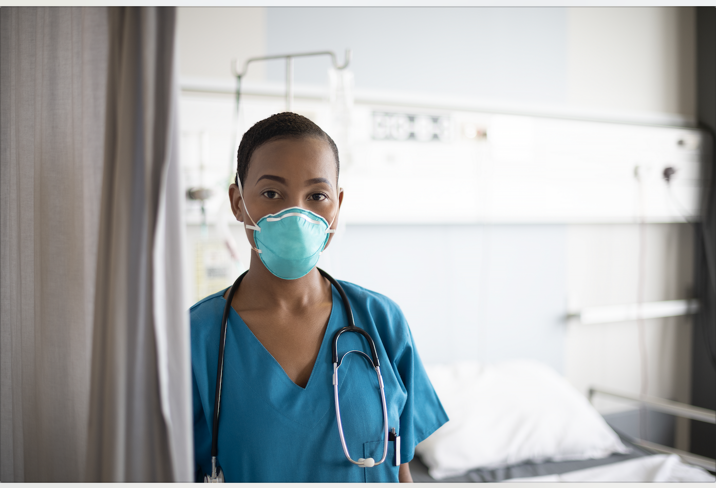 This is a photo of a nurse wearing an N-95 mask and standing by hospital curtains. KleenEdge and CME Corp partner to present Smart Curtain technology.